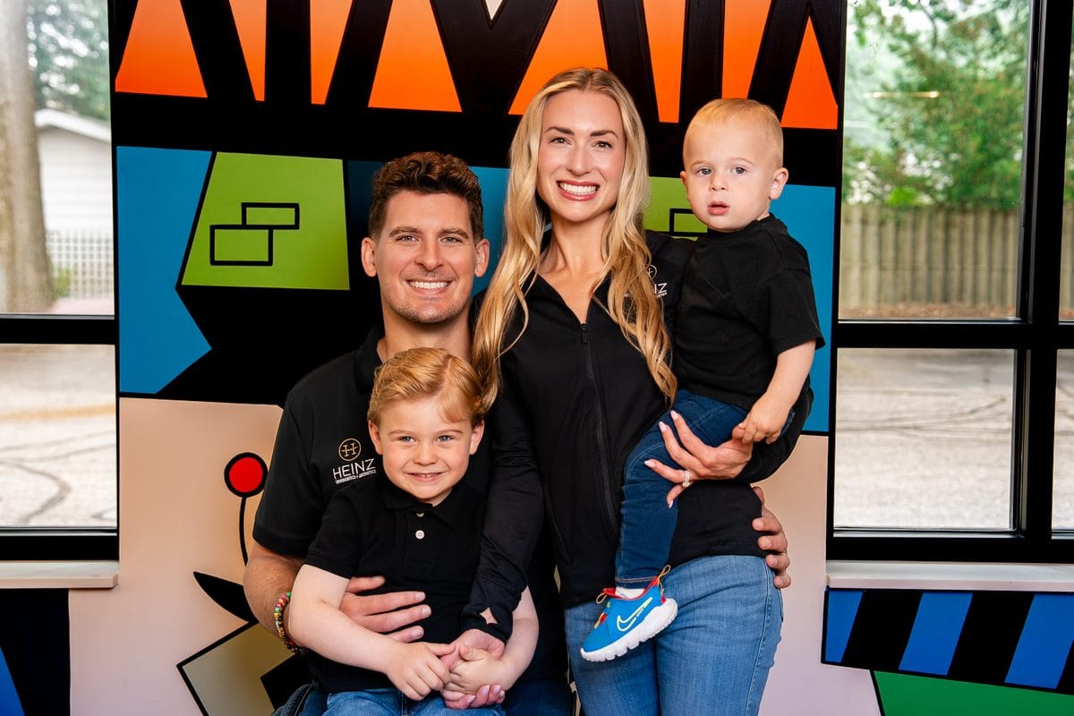 Dr. Jeffrey Heinz with his wife and two sons in front of the office mural